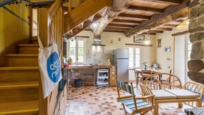Un interno rustico con una scala in legno, un angolo cottura e un'area pranzo con mobili in legno.