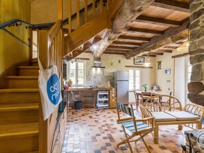 Ein rustikales Interieur mit einer Holztreppe, einer Küchenzeile und einem Essbereich mit Holztischen und -stühlen.