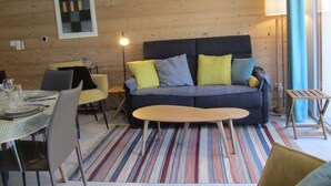 A cozy room with a sofa, chairs, a dining table, and a lamp. - Spacious apartment mountain view - 6 guests (Les Contamines-Montjoie)