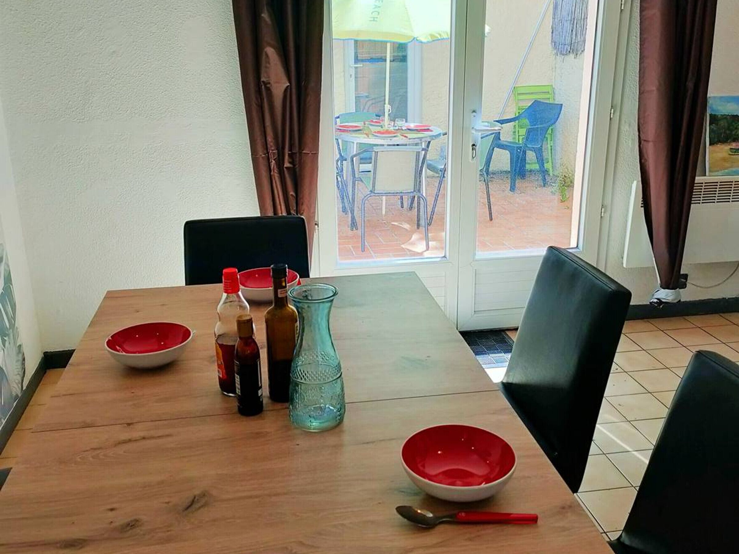 Una mesa de comedor con sillas, una ventana con cortinas y vista al exterior.