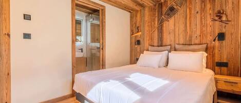A bedroom with a wooden ceiling, a bed with white bedding, a wooden headboard, and a nightstand.