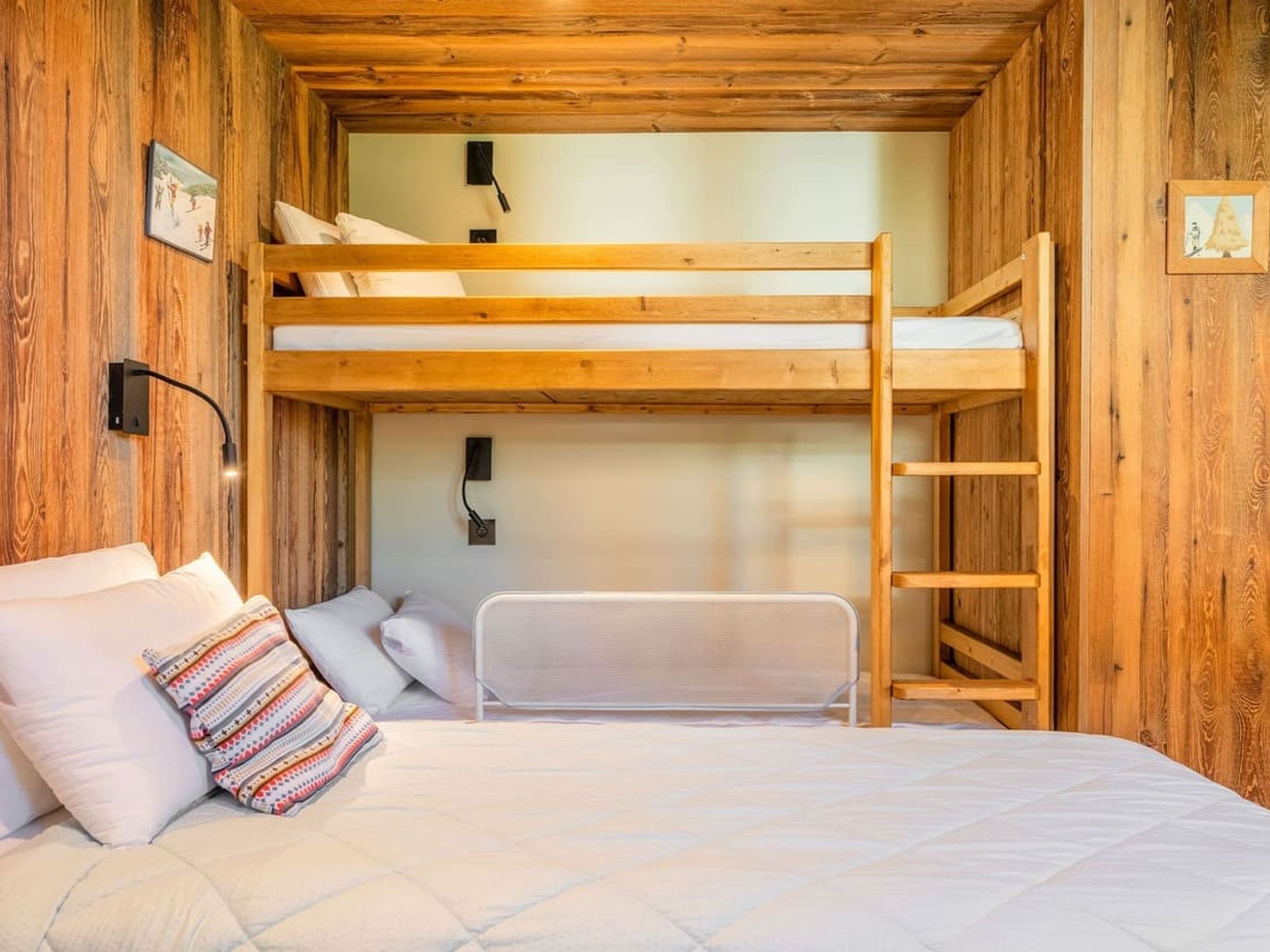 A bunk bed room with a wooden ceiling, a ladder, and a bed with pillows.