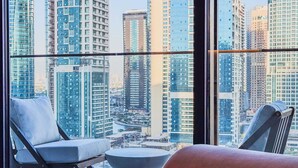 A modern hotel room with a large window overlooking a cityscape of high-rise buildings. - Premium Home, Designer Interiors, Near by JBR (Dubai)