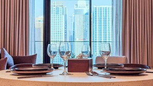 A dining table set for four with wine glasses, plates, and cutlery, positioned in front of a window with a cityscape view. - Premium Home, Designer Interiors, Near by JBR (Dubai)