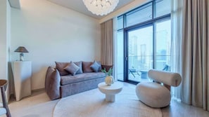Ein modernes Wohnzimmer mit einer Couch, einem runden Couchtisch, einer Stehlampe und Blick auf die Stadt durch große Fenster.