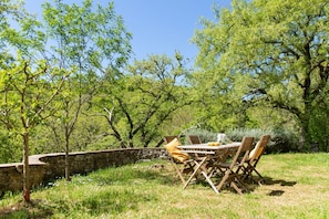 An outdoor dining area with a stone wall, wooden table, and chairs.