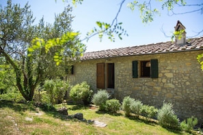 A stone building with a tiled roof, a wooden door, and a chimney.