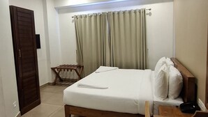 A hotel room with a bed, a desk, a chair, a wardrobe, and a door. - 18 ROOMS BY OLAN (Thrissur)