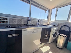 Eine moderne Küche mit Geschirrspüler, Waschmaschine und Spüle mit Fenster darüber.
