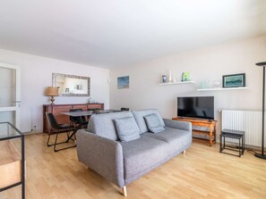 A living room with a grey sofa, a TV, a dining table with chairs, and a lamp. - Charming apartment near the port - 6 guests (Hendaye)