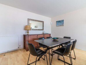 A dining area with a table, chairs, a lamp, a cabinet, and a painting on the wall. - Charming apartment near the port - 6 guests (Hendaye)