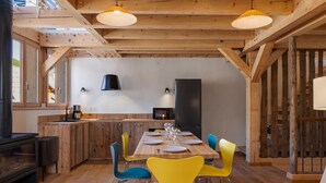 A wooden interior with a dining table, chairs, and a kitchen area. - Unique duplex, mountain view, 8 guests (Le Monêtier-les-Bains)