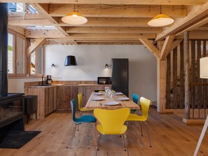 A wooden interior with a dining table, chairs, and a kitchen area. - Unique duplex, mountain view, 8 guests (Le Monêtier-les-Bains)