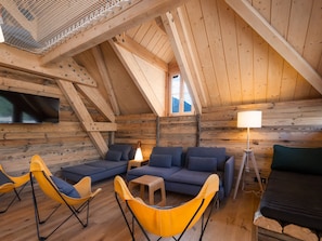 A cozy attic room with a wooden ceiling, a sofa set, yellow chairs, a small table, and a lamp. - Unique duplex, mountain view, 8 guests (Le Monêtier-les-Bains)
