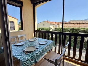 Ein Balkon mit Tisch und Stühlen für zwei Personen und Blick auf Wohnhäuser.