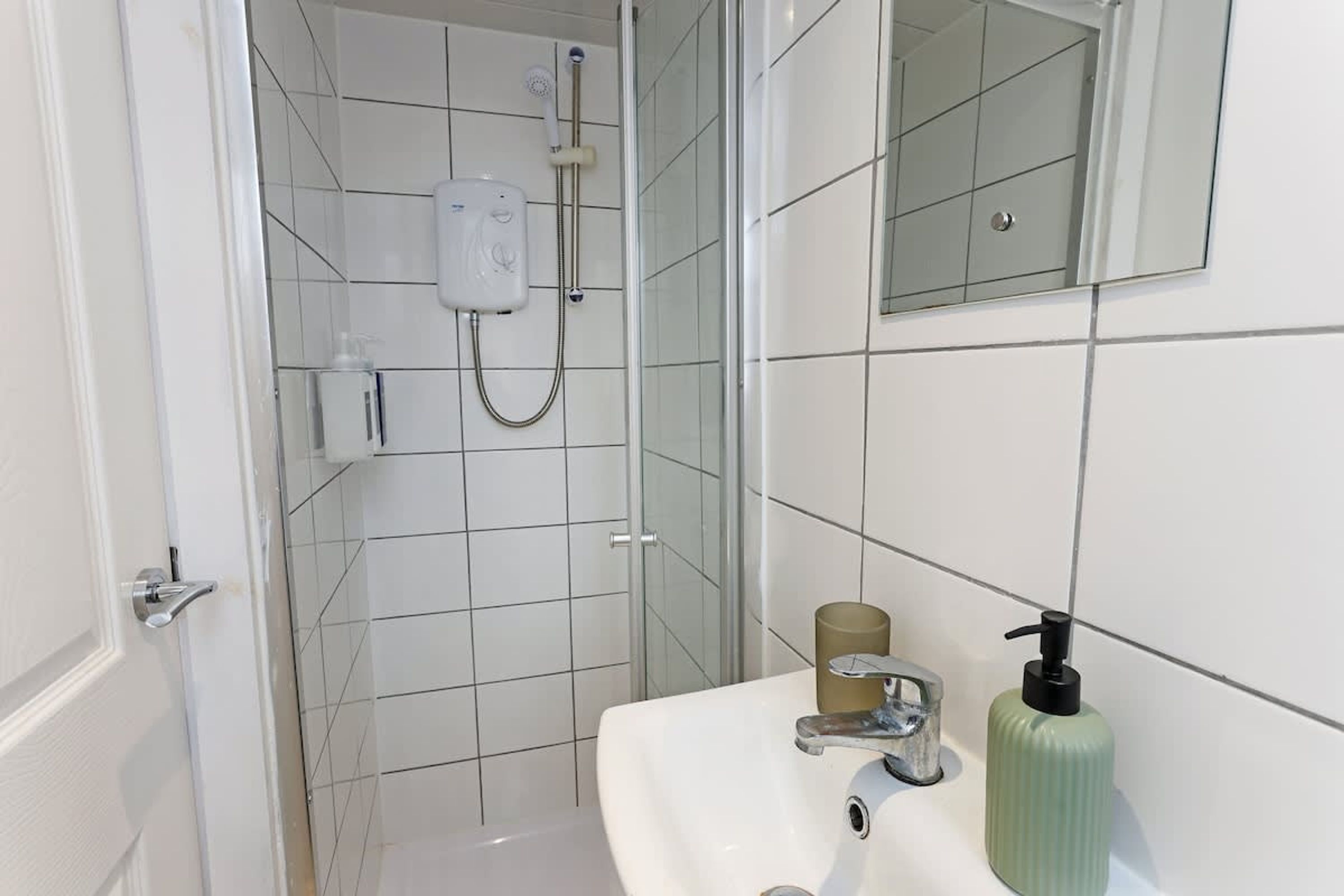 A bathroom with a shower, a sink, a mirror, and a toilet.