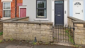 A row of terraced houses with distinct front doors, windows, and a stone wall in the foreground. - Perfect Booking 4 Bed Highfield House w 4 Baths (Sheffield)