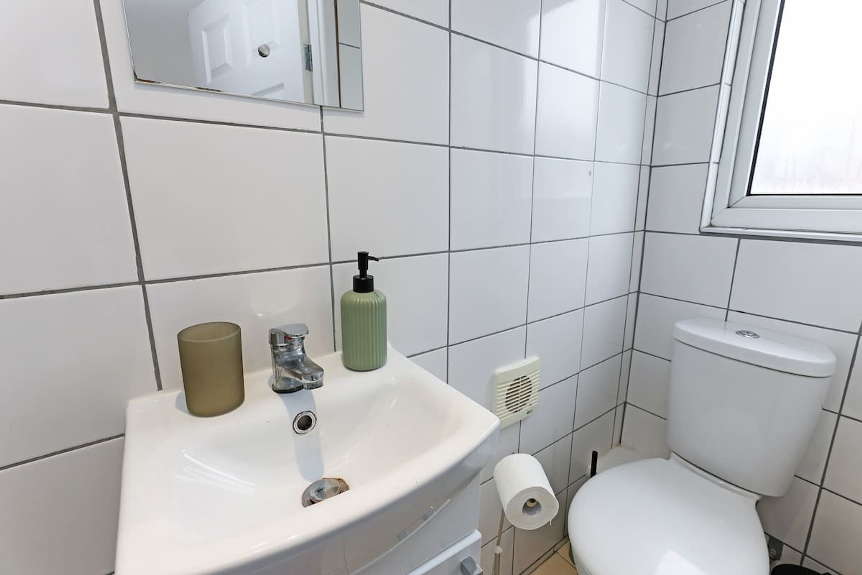 A bathroom with a white sink, toilet, and mirror.