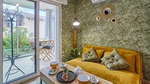 Une pièce comprenant un canapé, une table avec un plateau, une fenêtre et un appareil de climatisation.
