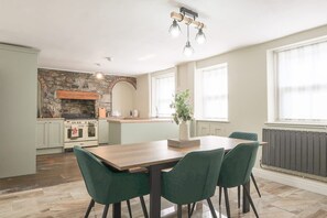 Eine moderne Küche mit Steinrückwand, Holzschränken und einem eingebauten Backofen.