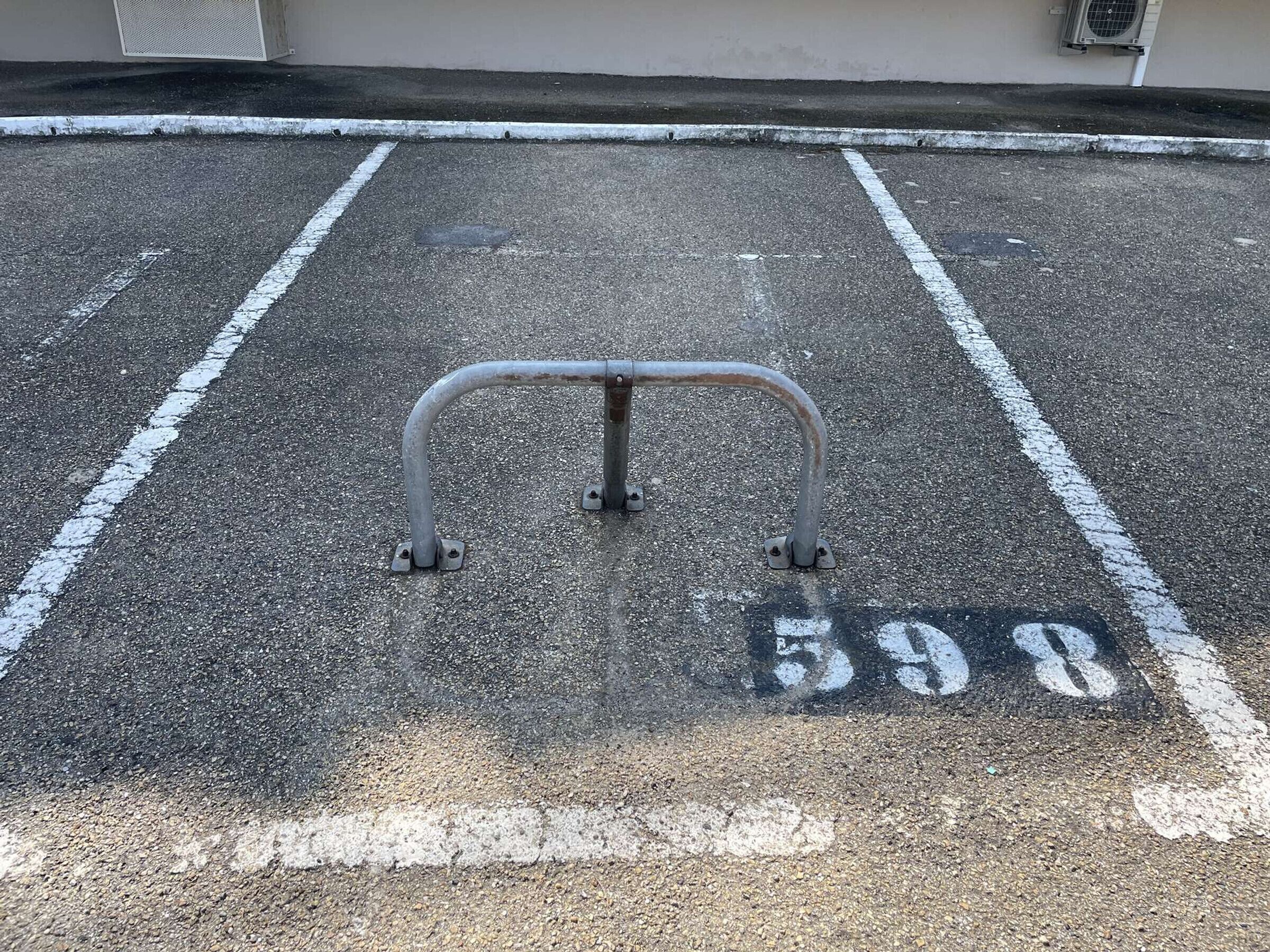 Posto auto con barriera metallica e il numero 598 dipinto a terra.