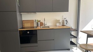 Et moderne køkken med lysegrå skabe, en træbordplade, en kaffemaskine og en vask.