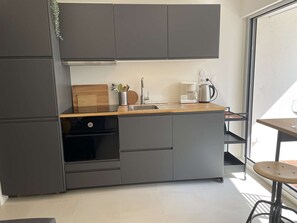 Eine moderne Küche mit grauen Schränken, einer Holzarbeitsplatte, einer Kaffeemaschine und einem Spülbecken.