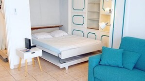 A bedroom with a bed, a desk, a chair, and a wardrobe. - Studio sea view, parking and air conditioning (Canet-Plage)