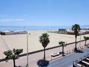 Ein Strand mit blauem Himmel, sandigem Ufer und einigen Palmen.