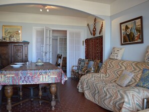Ein Zimmer mit Esstisch, Stühlen, einer Couch und einem Bild an der Wand.
