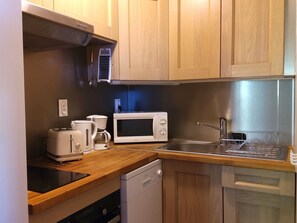 Eine kleine Küche mit Mikrowelle, Toaster, Kaffeemaschine und Geschirrspüler.