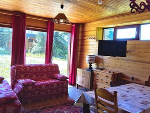 Ein gemütliches Zimmer mit einer Couch, einem Tisch, einem Fernseher und einem Schrank.