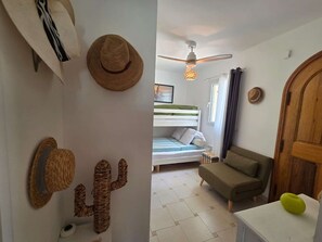 A room with a bed, a ceiling fan, a cactus decoration, and a wooden door. - Apartment with sea view - 4 guests (Lumio)