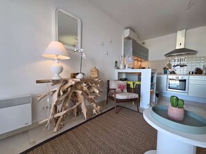 A modern kitchen with a wooden side table, a chair, and a small table with a potted plant. - Apartment with sea view - 4 guests (Lumio)