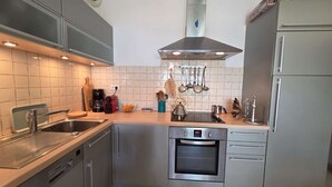 Cozinha moderna com lava-louças, forno e exaustor de aço inoxidável.