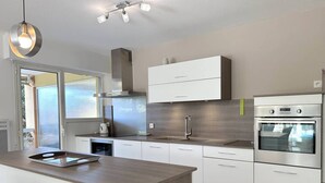 Una cocina moderna con una isla central, electrodomésticos de acero inoxidable y vistas a través de un ventanal.