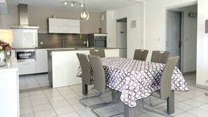 Una cocina moderna con una isla central, mesa de comedor con sillas y una lámpara colgante.