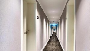 Un pasillo de hotel con puertas numeradas 104 y 105, suelo alfombrado e iluminación empotrada en el techo.