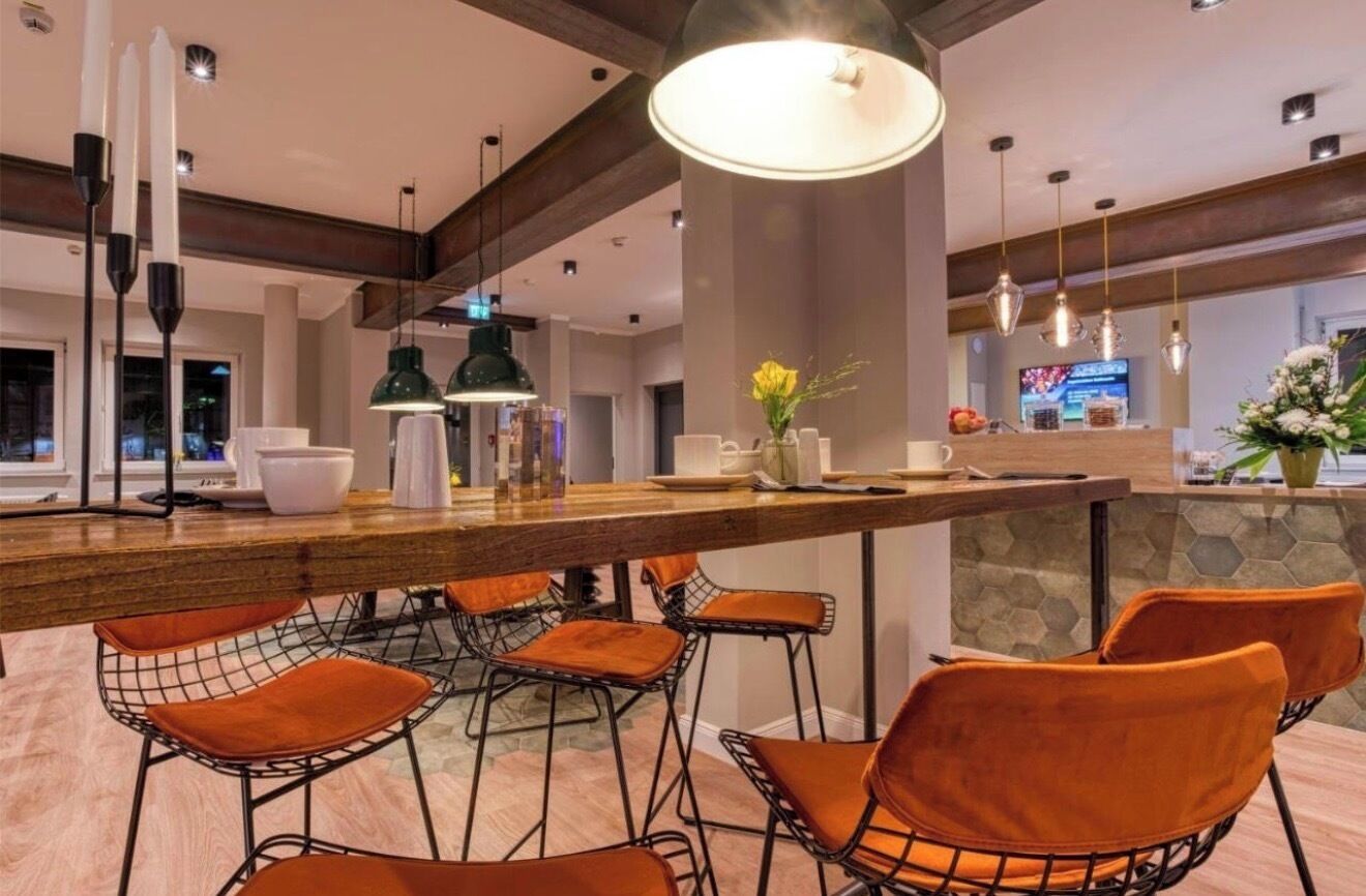 A modern kitchen with a bar area, bar stools, pendant lighting, and a stone accent wall.