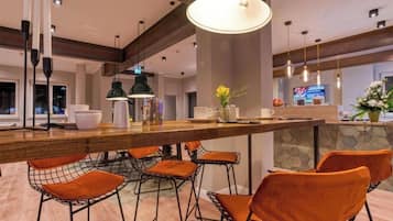 A modern kitchen with a bar area, bar stools, pendant lighting, and a stone accent wall.