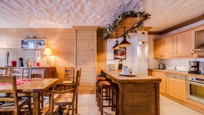 Une cuisine chaleureuse avec des meubles en bois, un îlot central et un coin repas avec des chaises.