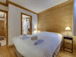 Ein Hotelzimmer mit einem großen Bett, Holzwänden, einem Spiegel und einem Nachttisch mit einer Lampe.