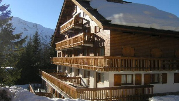 A multi-story wooden chalet with balconies, surrounded by snow and mountains. - Bright apartment near slopes - 6 guests (Méribel)