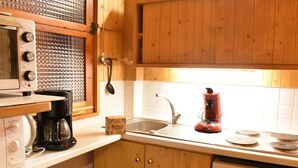 A kitchen with wooden cabinets, a microwave, a coffee maker, a blender, and a dishwasher. - Bright apartment near slopes - 6 guests (Méribel)