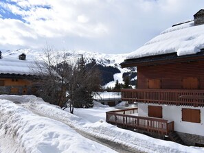 Ein verschneites Bergdorf mit Holzhäusern, einer Holztreppe und einem klaren Himmel.