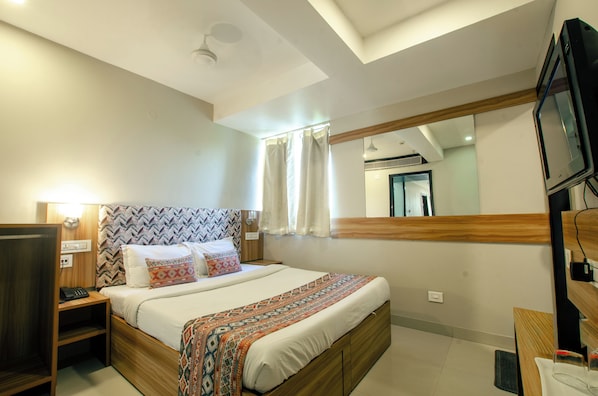 A hotel room with a bed, bedside table, TV, and a mirror. - Hotel Jullundur 18 (Chandigarh)