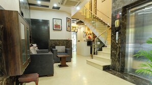 Un hall con mostrador de recepción, zona de estar, escalera y ascensor.