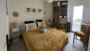 Ein Schlafzimmer mit Bett, Nachttischen, einem Kleiderschrank, einer Pendelleuchte und einem Fenster.