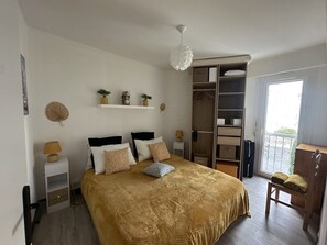 Ein Schlafzimmer mit Bett, Nachttischen, einem Kleiderschrank, einer Pendelleuchte und einem Fenster.