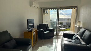 Ein Wohnzimmer mit Fernseher, zwei Sofas, einem Couchtisch mit Zitronen und einem Balkon mit Tisch und Stühlen.